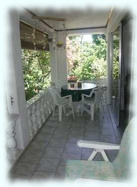 Die Terrasse mit einem Liegestuhl im Vordergrund und einer Sitzgruppe am anderen Ende