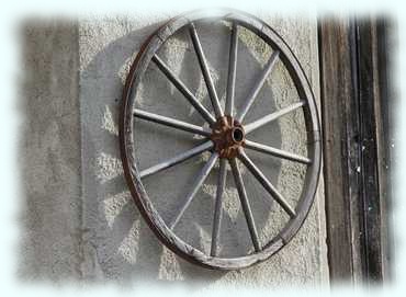Wagenrad an einer Hauswand in Obertrum